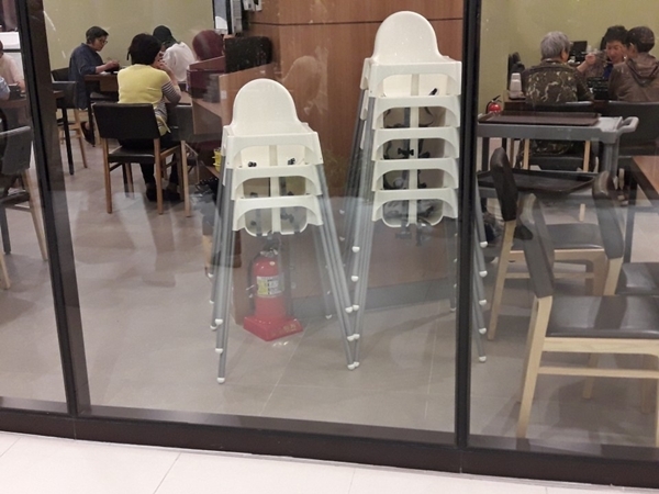 롯데몰 수지점 ?층 식당 소화기 위로 유아용 의자가 쌓여 있다.