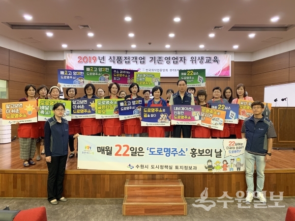 식품접객업소 종사자들이 도로명주소를 홍보하는 손팻말을 들고 있다.(사진=수원시)