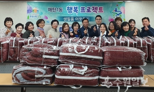 매탄1동 지역사회보장협의체 위원들이 이불 앞에서 기념사진을 찍고 있다.(사진=매탄1동)