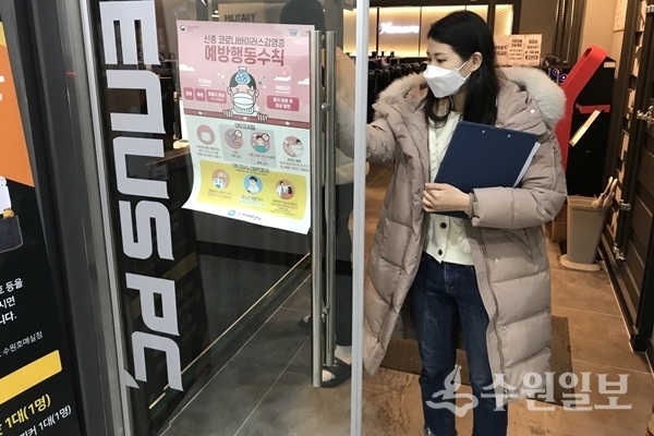권선구 관계자가 관내 PC방 출입구에 신종 코로나바이러스 예방수칙 안내문을 붙이고 있다. (사진=권선구)