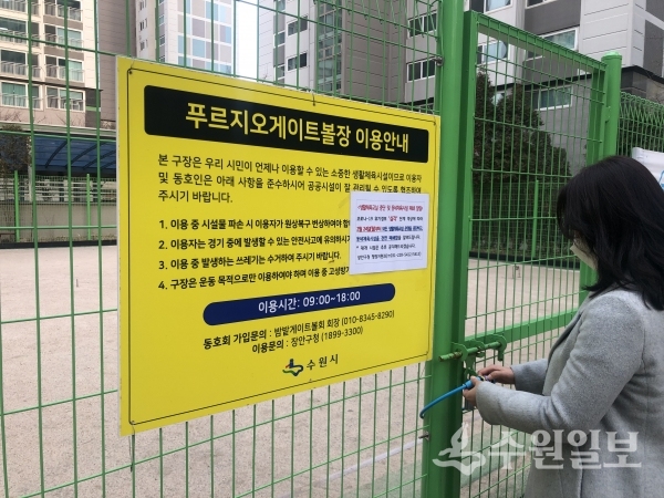 장안구 관계자가 천천푸르지오 아파트 내 게이트볼장 출입구에 폐쇄 안내문을 붙이고 있다.(사진=장안구)
