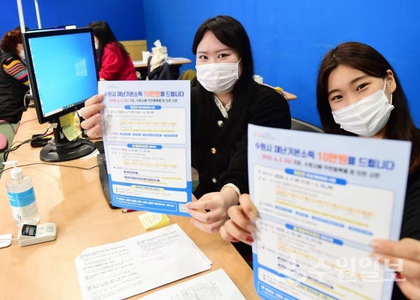 수원시 재난기본소득 접수 안내를 맡은 청년인턴이 홍보물을 들어보이고 있다.(사진=수원시)