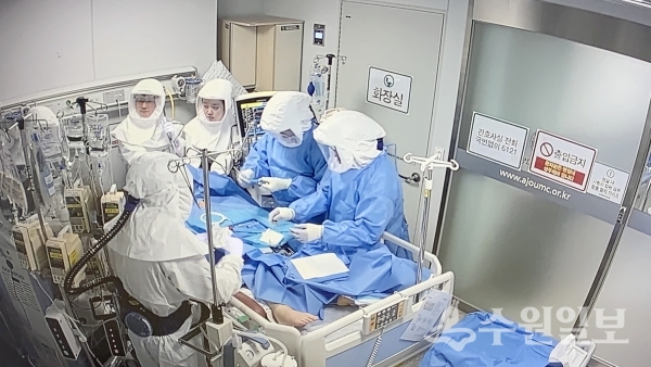 방호복을 갖춘 의료진이 인공호흡기 치료환자에게 기관지 내시경과 기관절개술을 시행하고 있다.(사진=아주대의료원)