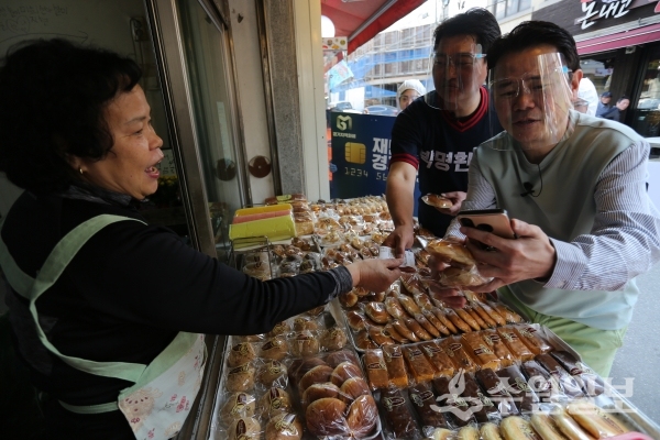 강성범(오른쪽)과 박명환(가운데)이 구 매탄시장 빵집에서 경기지역화폐로 빵을 구매하고 있다.(사진=경기도)