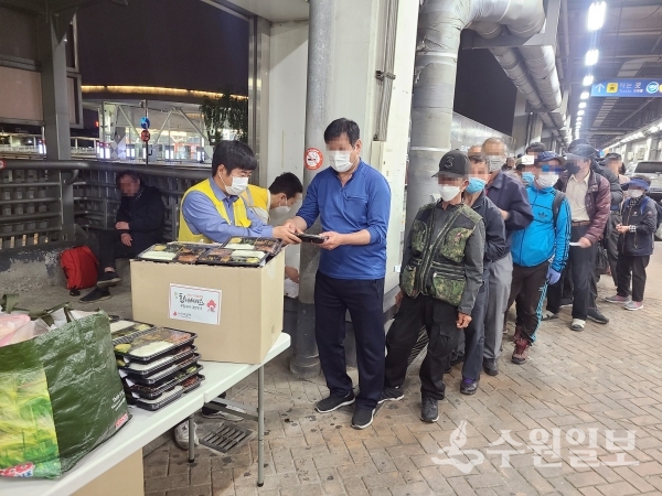 봉사자들이 노숙인에게 도시락을 나눠주고 있다.(사진=수원시)