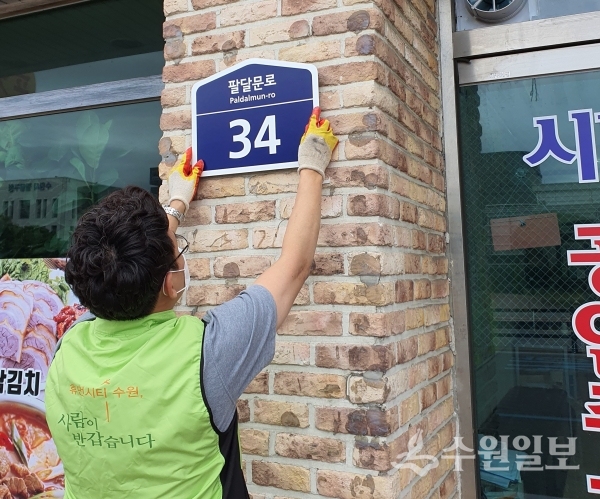 팔달구 관계자가 도로명주소 건물번호판을 달고 있다.(사진=팔달구)