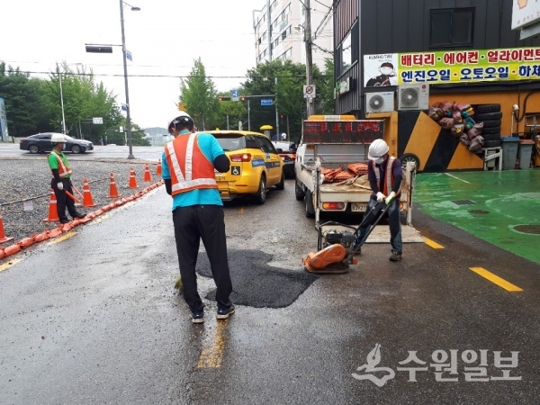 장안구 관계자들이 도로에 생긴 구멍을 아스콘으로 복구하고 있다.(사진=장안구)