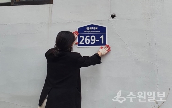 영통구 관계자가 도로명주소 건물번호판을 붙이고 있다.(사진=영통구)