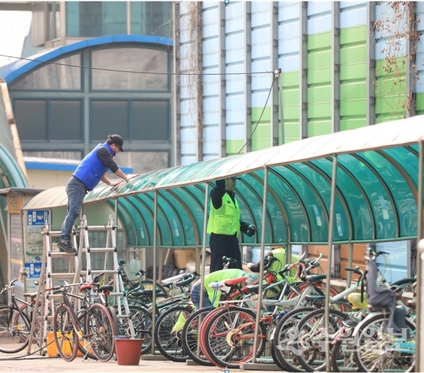 작업자가 화서역 앞 자전거 보관대를 세척하고 있다.(사진=수원시)
