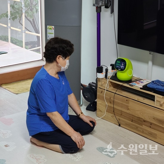 연무동에 거주하는 한 어르신이 거실에 설치한 ‘AI 케어로봇 시니어’를 살펴보고 있다. (사진=수원시)