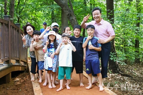 김성제 의왕시장(오른쪽)이 아이들과 맨발로 황톳길을 걸으면서 기념촬영을 하고 있다. (사진=의왕시)
