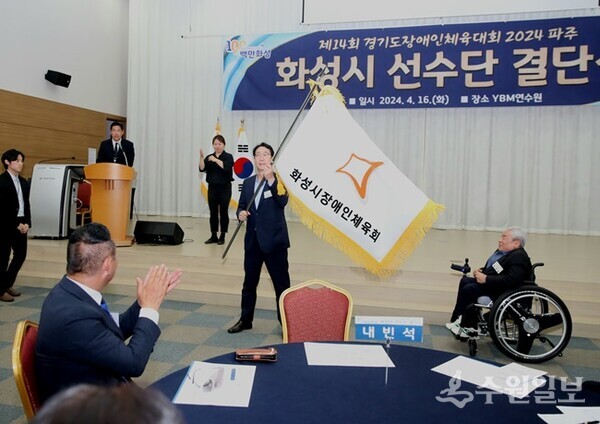 정명근 화성시장이 제14회 경기도장애인체육대회 출전 결단식에서 선전을 당부하며 선수단기를 흔들어 보이고 있다. (사진=화성시)