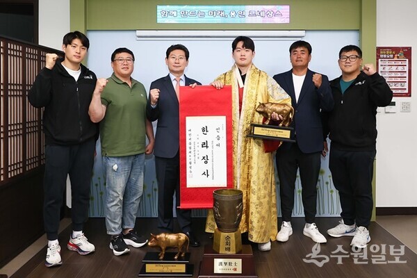 이상일 용인시장(온쪽 세번쨰)이 개인 통상 4번째 한라장사에 등극한 박민교 선수(오른쪽 세번째)와 단체전 우승을 차지한  용인직장운동경기부 씨름단으로부터 우승트로피를 전달받은 뒤 함께 기념촬영을 하고 있다. (사진=용인시)