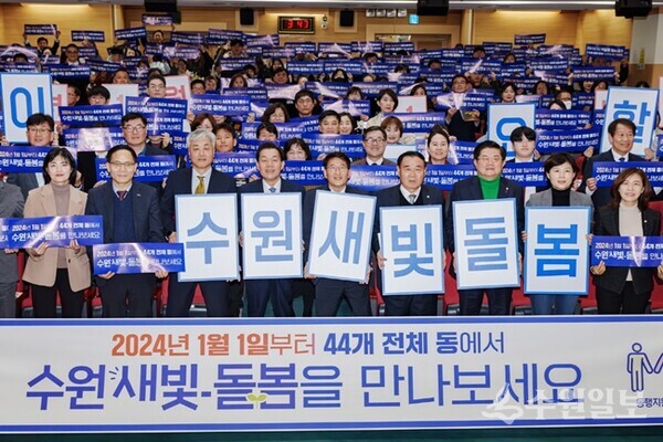 지난해 12월 수원시 관계자들이 수원새빛돌봄 전체 동 확대를 홍보하는 손팻말을 들어 보이고 있다.(사진=수원시)