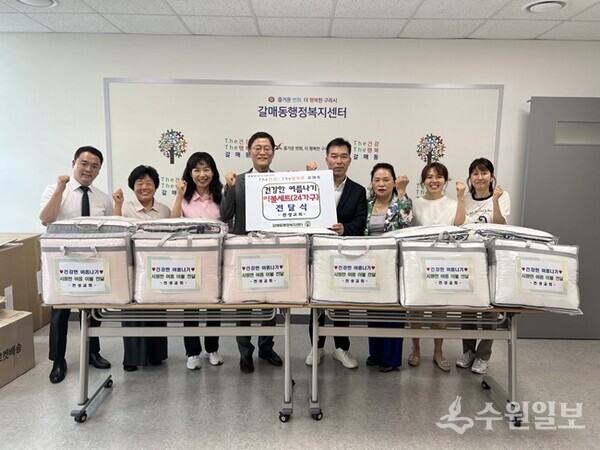 강석우 구리 천성교회 담임목사(왼쪽 네번째)와 성도들이 남상익 갈매동장(오른쪽 네번째)에게 여름 이불세트를 전달한 뒤 기념촬영을 하고 있다. (사진=구리시)