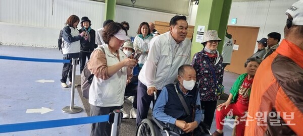 김구영 개혁신당 구리시 당협위원장이 휄체어를 탄 어르신을 모시고 이동하고 있다. (사진=구리아리랑컨텐츠협회)