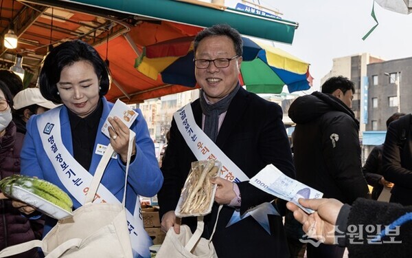 시석중 경기신용보증재단 이사장(오른쪽)이 정윤경 경기도의회 부의장과 ‘전통시장 활성화를 위한 설맞이 장보기'를 하고 있다.(사진=경기신보)