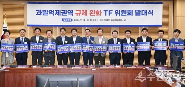 지난해 7월 국회에서 열린 ‘과밀억제권역 규제완화 TF 위원회 발대식’에서 참석자들이 과밀억제권역 완화를 위한 손팻말을 들고 있다.(사진=수원시)