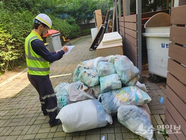 새빛 환경수호자가 한 공동주택단지의 쓰레기 배출량을 현장 점검해 평가표에 적고 있다.(사진=수원시)