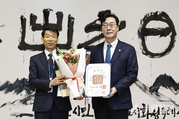 정명근 화성특례시장(오른쪽)이 시무식에서 강래향 행정종합관찰관에게 대통령 표창을 전달한 뒤 기념촬영을 하고 있다. (사진=화성시)