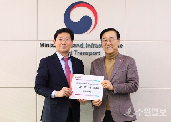 26일 정부세종청사에서 이상일 용인특례시장(왼쪽)이 김윤덕 국토교통부장관에게 '용인 첨단시스템반도체 국가산업단지 이전 반대' 목소리를 담은 '110만 용인시민 서명부'를 전달한 뒤 포즈를 취하고 있다. (사진=용인시)