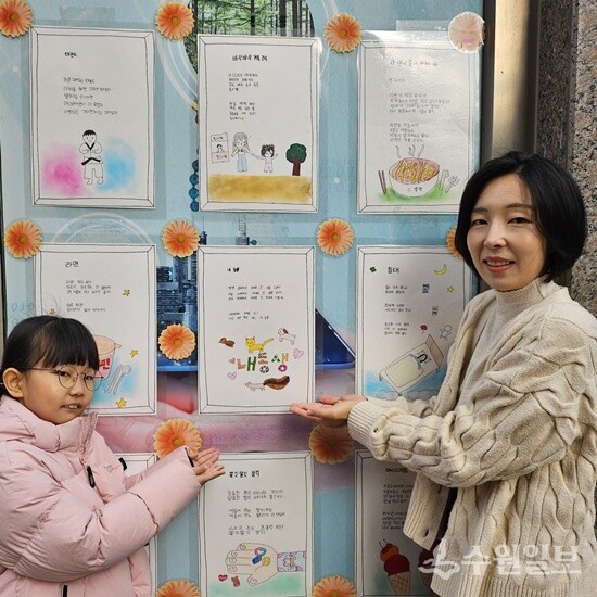 아이의 성장을 담은 동시 작품 앞에서 김가온 학생과 학부모가 감동을 나누고 있다. (사진=한빛마을센터)