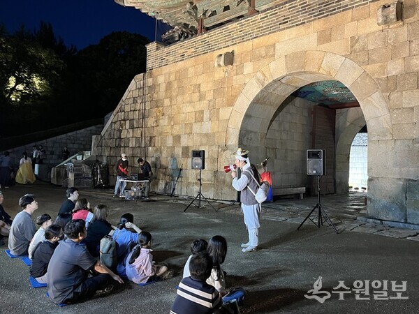 이야기꾼이 장안문 앞에서 관광객들에게 수원화성에 얽힌 숨은 이야기를 들려주고 있다. (사진=수원문화재단)