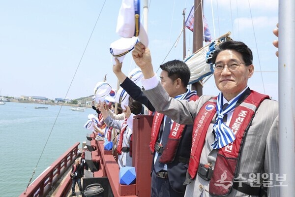 전곡항 앞바다를 순항하는 조선통신사선 선상에서 윤성진 화성특례시장 권한대행과 시민 탑승객들이 환영하는 관람객들을 향해 모자를 흔들며 화답하고 있다. (사진=화성시)