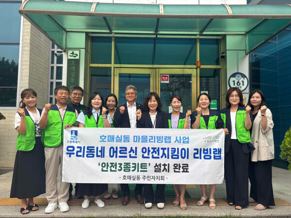 호매실동 주민자치회 관계자들이 ‘안전 3종 키트’ 설치 완료 기념 현수막을 들고 기념촬영을 하고 있다 (수원시 제공)